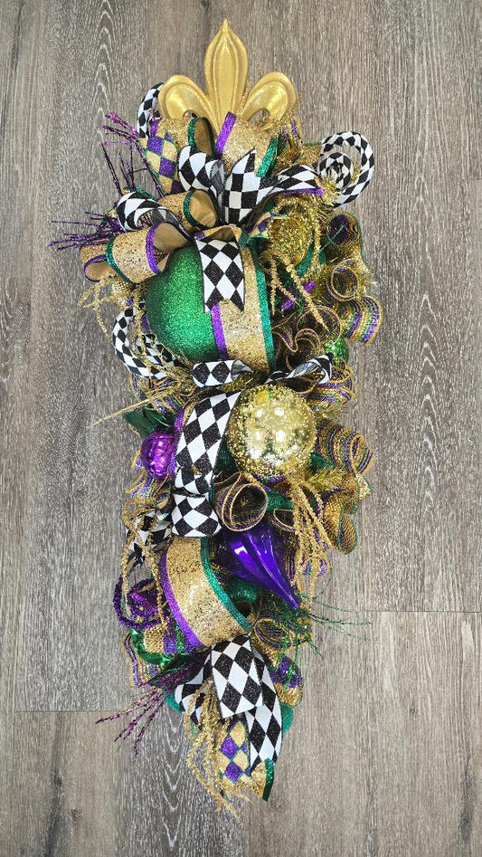Decorative Mardi Gras swag with colorful ribbons and beads on a wooden surface